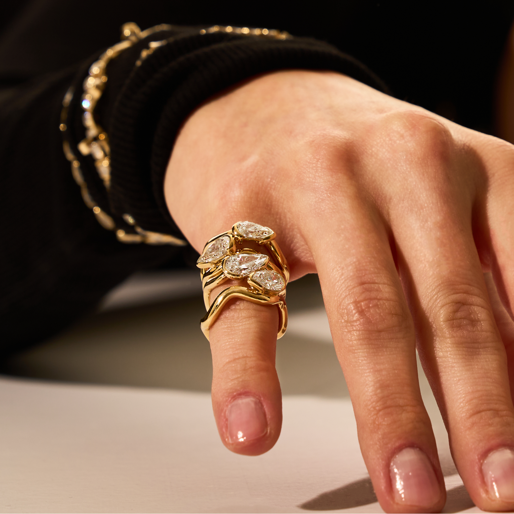 Hand wearing a gold ring with diamond accents on a neutral background