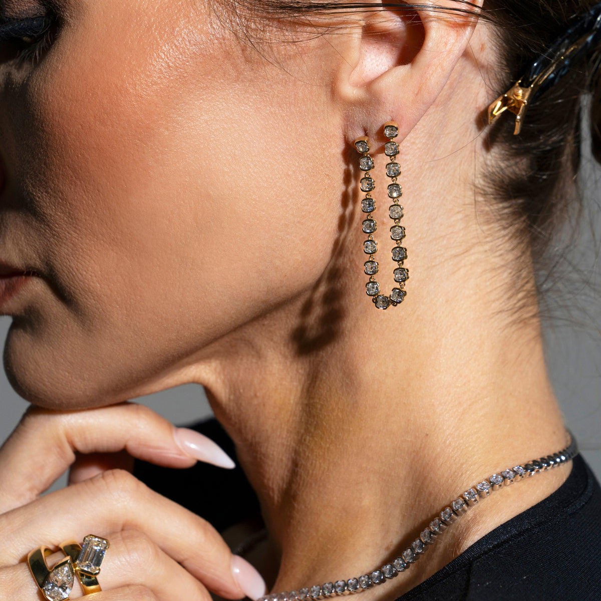 Close-up of a woman wearing gold dangle earrings and rings.