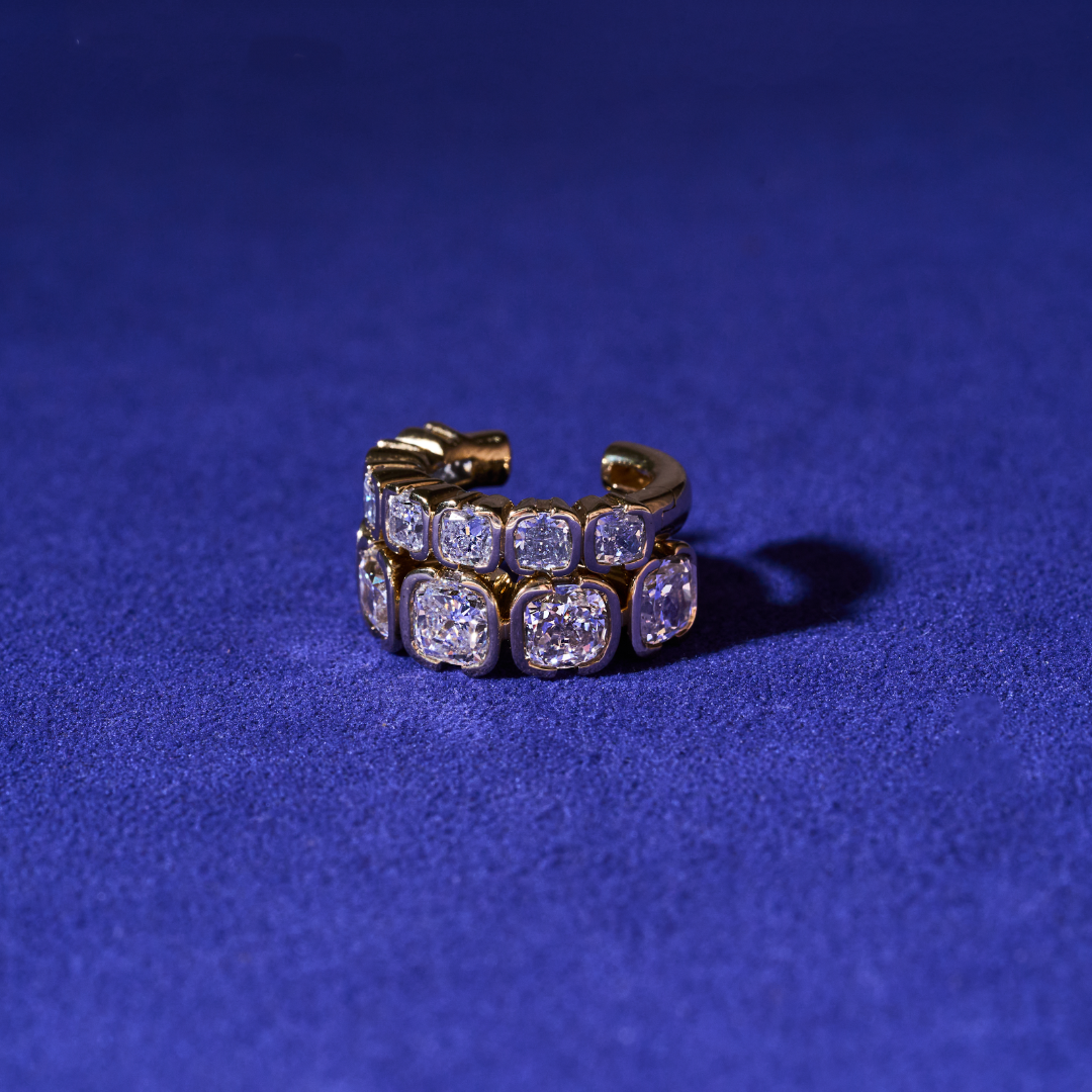 Lab diamond Muse Mega Cushion ear cuff in 14K yellow gold displayed on a blue surface.
