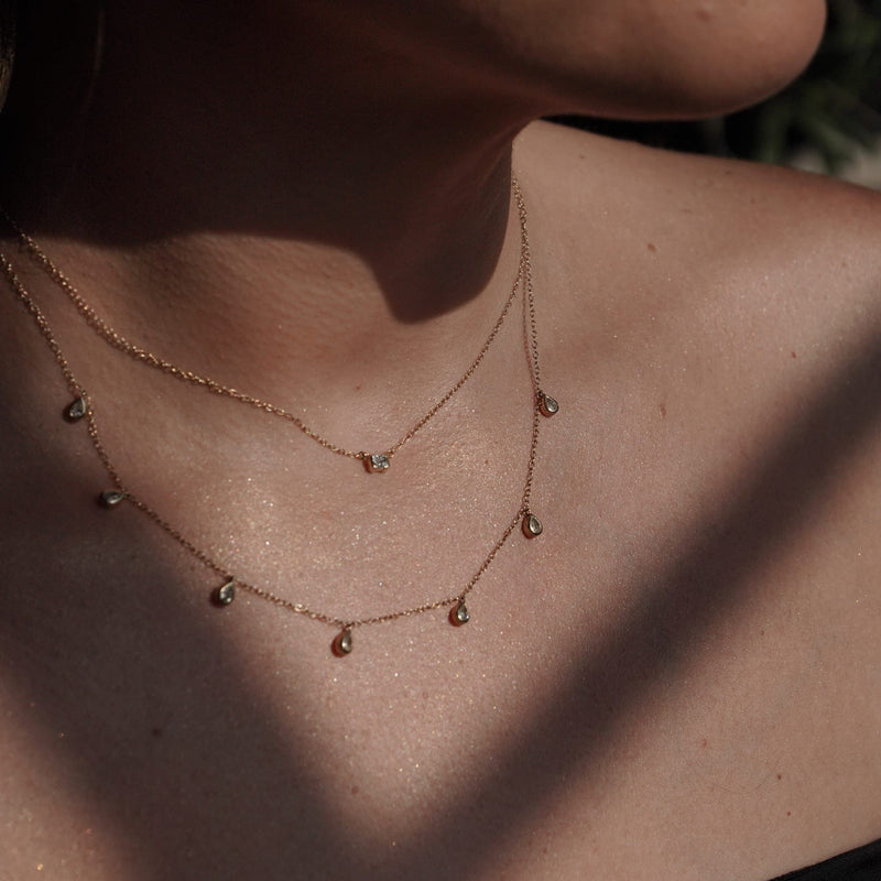 Model wearing the pendant layered with other SETTE pieces.