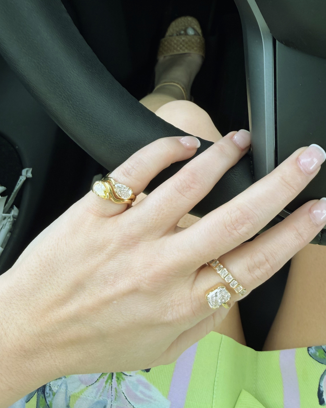 Woman driving with a pinky ring stack. 2 1 carat pinky rings. One of the white lab diamond and one yellow lab diamond. Paired with a Revel Pointer finger anchored with a 2 ct Radiant.