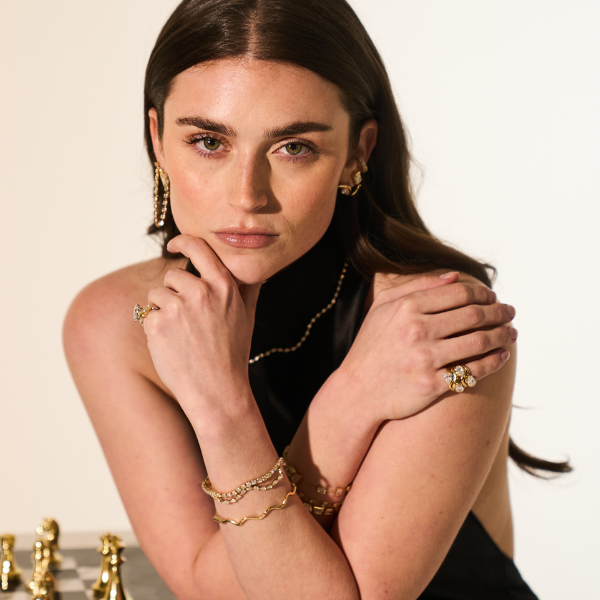Woman wearing gold jewelry with a chessboard in the background