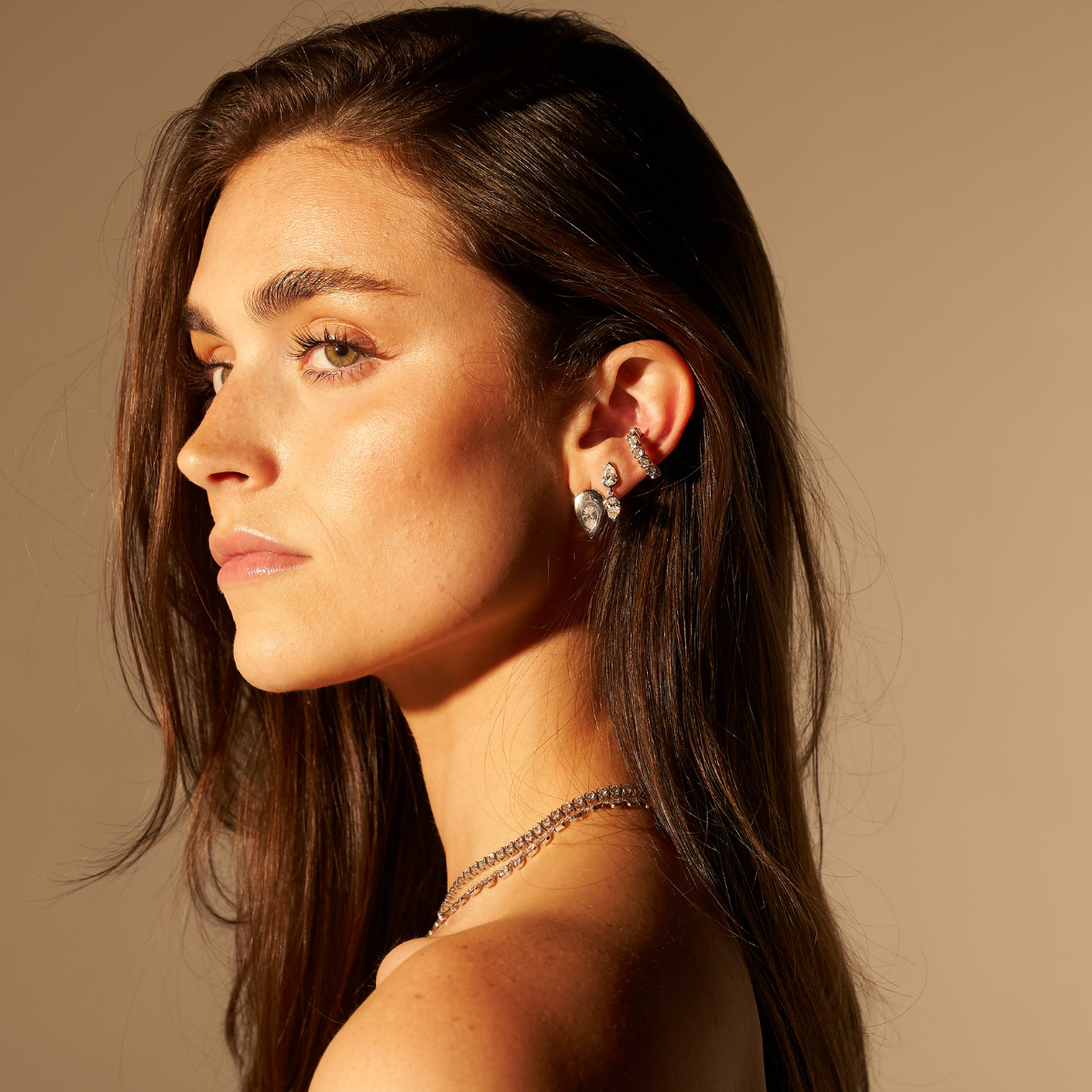 Model in profile wearing the SETTE Coquette Drop earrings in two-tone 14K gold, showing the drop on-ear with the white and yellow pear lab diamonds visible.